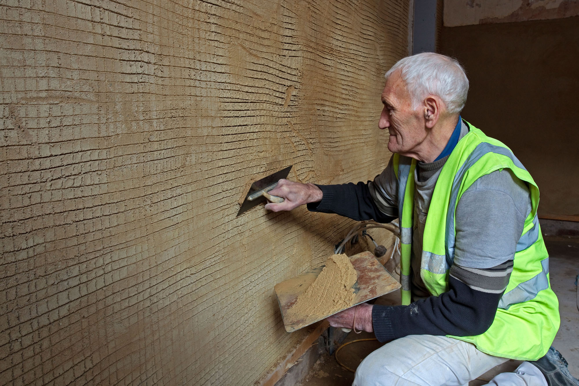 Traditional plasterer applying lime and mortar to a wall.