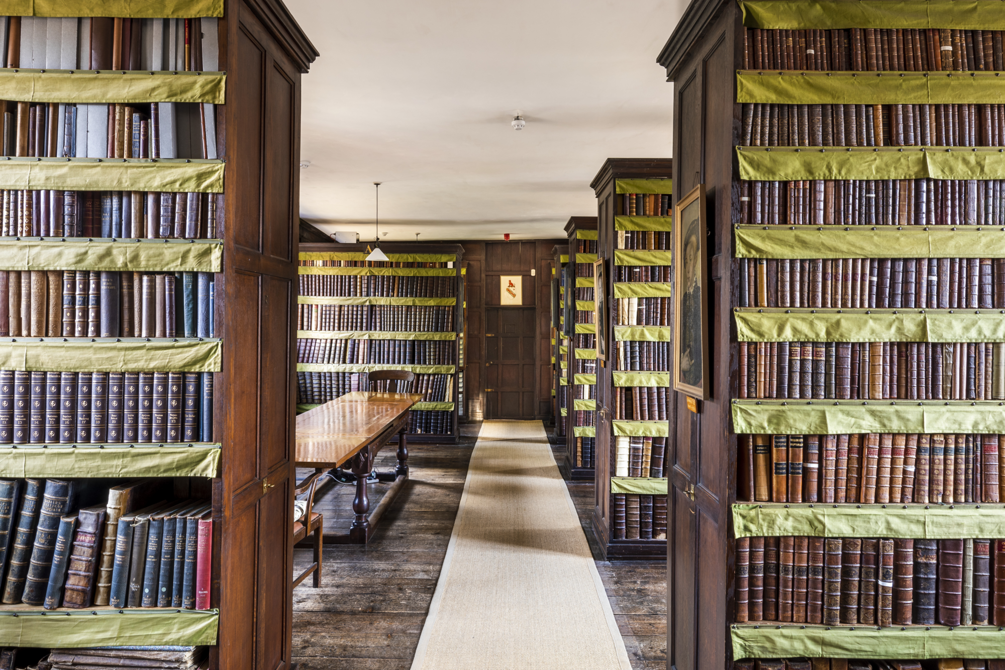 A library interior featuring wooden bookshelves lined with green fabric.