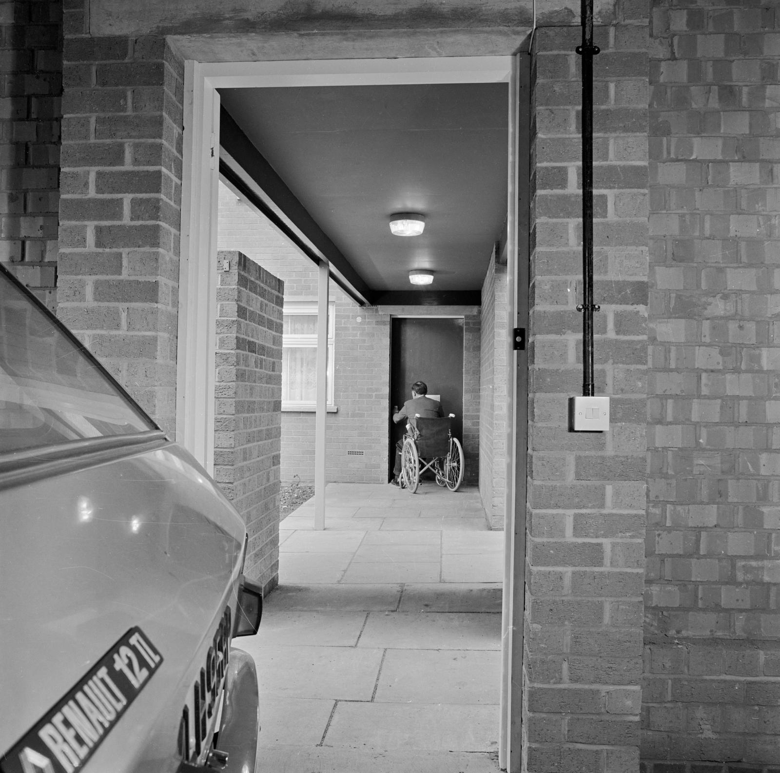 A man in a wheelchair unlocking the door to his sheltered accommodation.