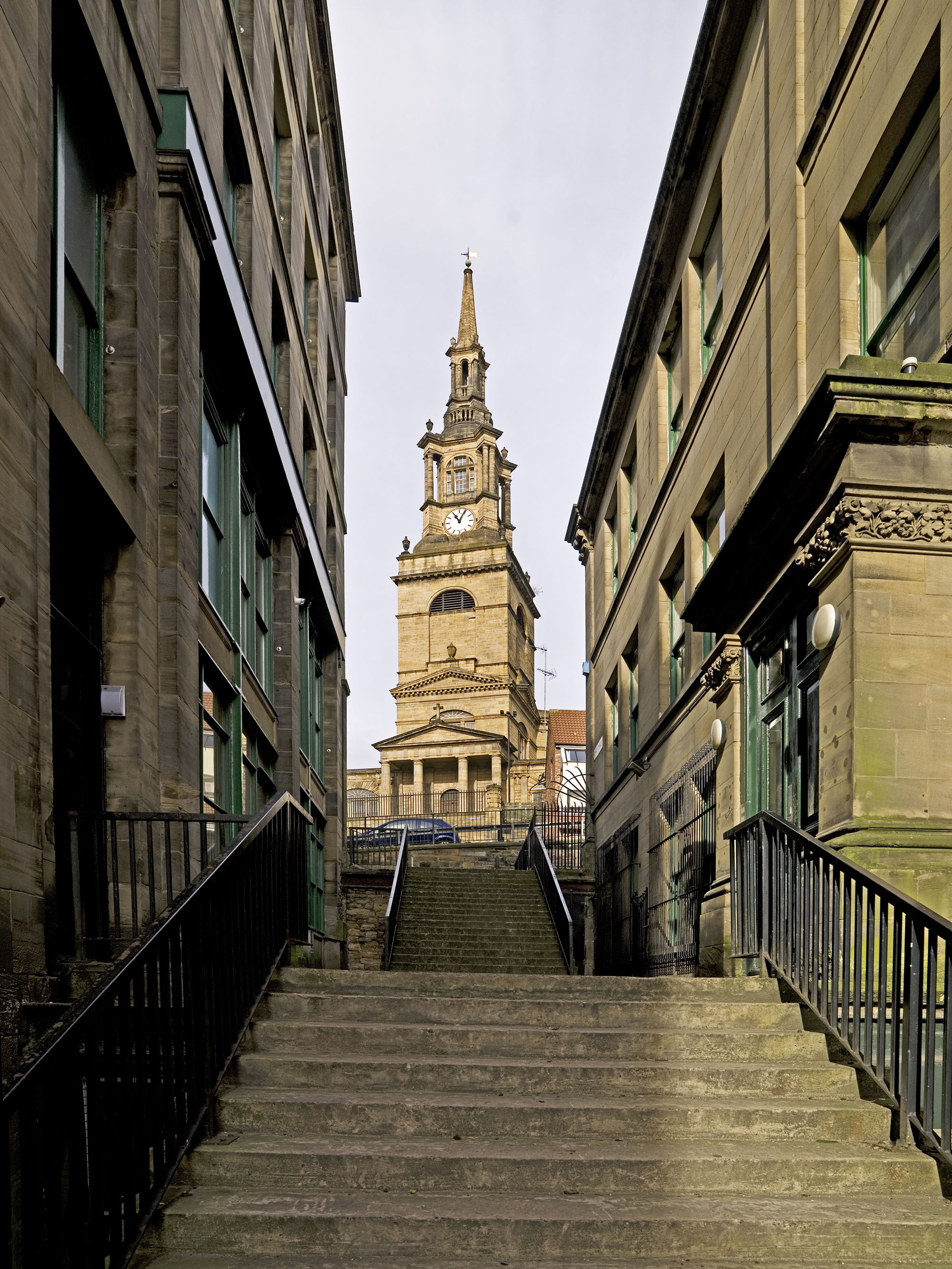 View of All Saints Church between rows of buildings