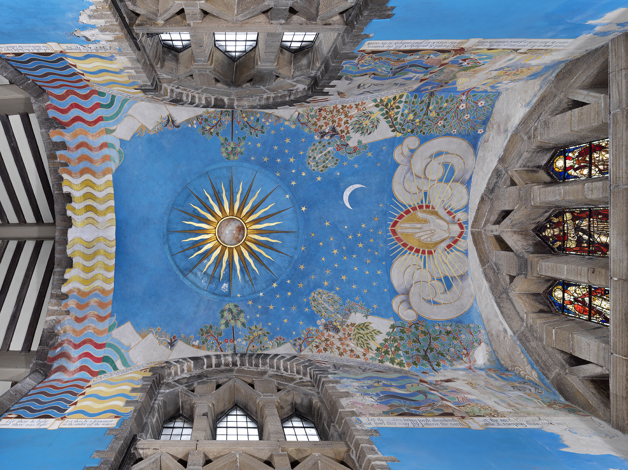 Church ceiling mural featuring sun, moon, stars, trees and a hand flanked by clouds, all against a bright blue background.