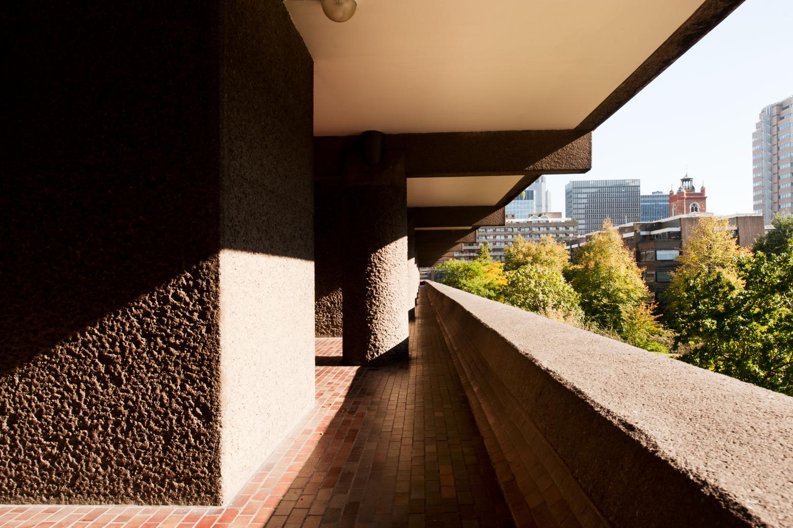 Terracotta tiled walkway along a line of bush-hammered concrete pillars.