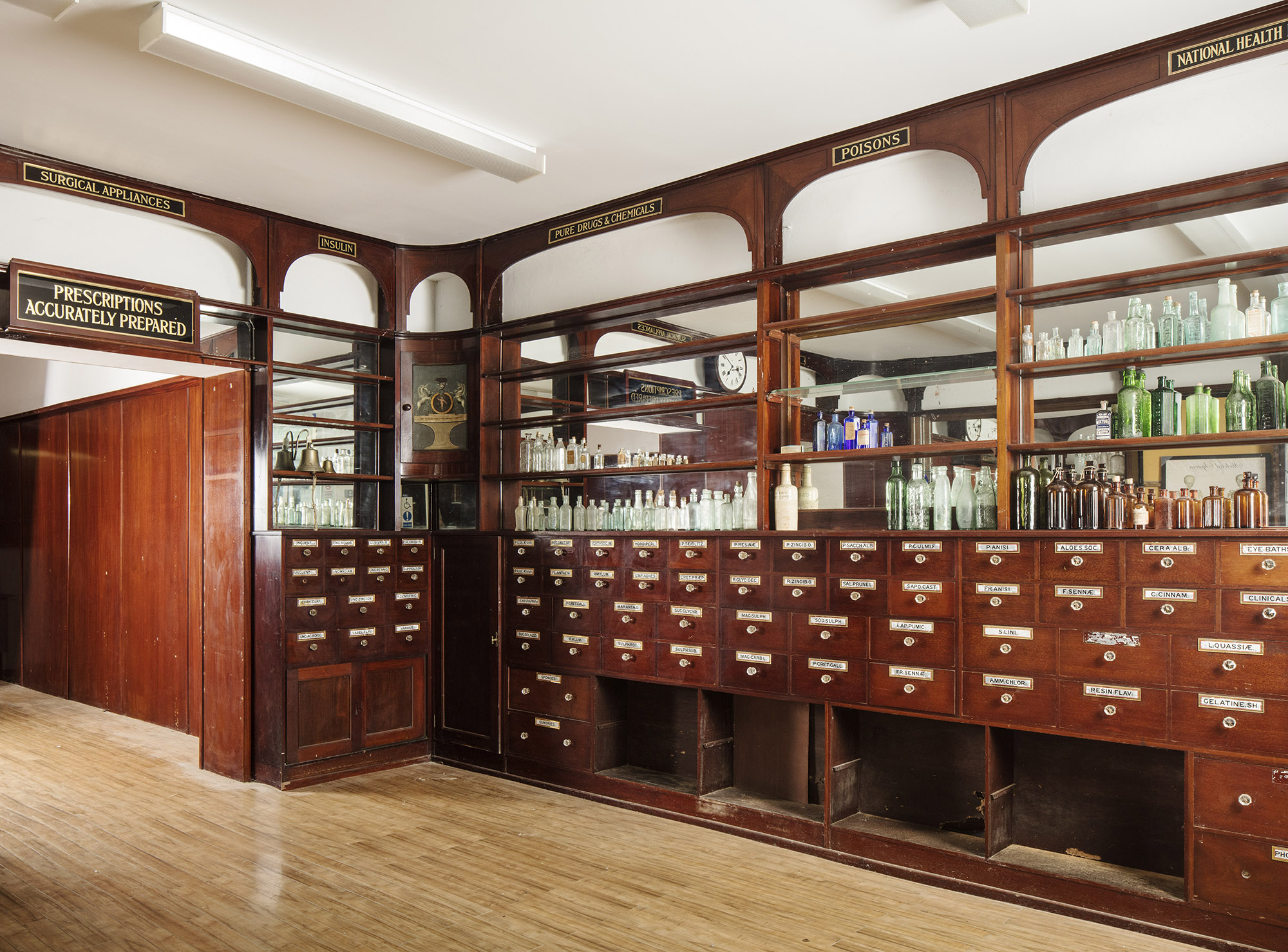 Interior of chemist shop with original wooden drawers and shelves displaying glass bottles.
