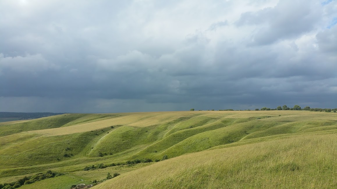 View of undulating downland under a stormy sky