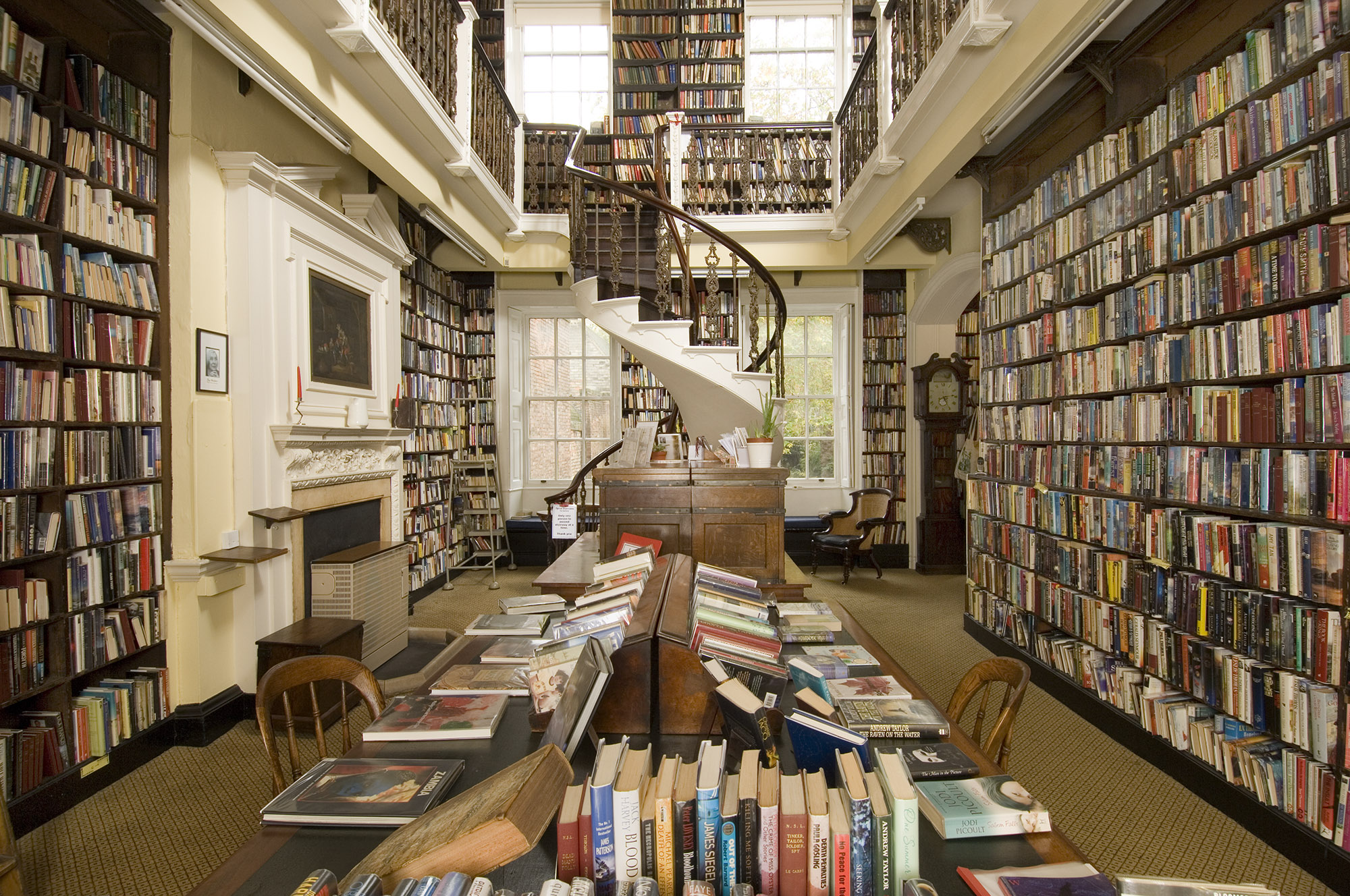 Photo of the inside of Bromley House Library, with shelves filled with books and a spiral staircase at the far end