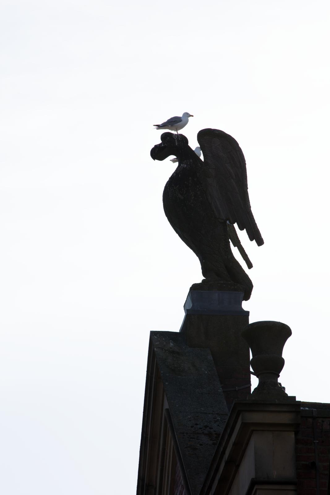 Carving of eagle with a seagull on top of it.