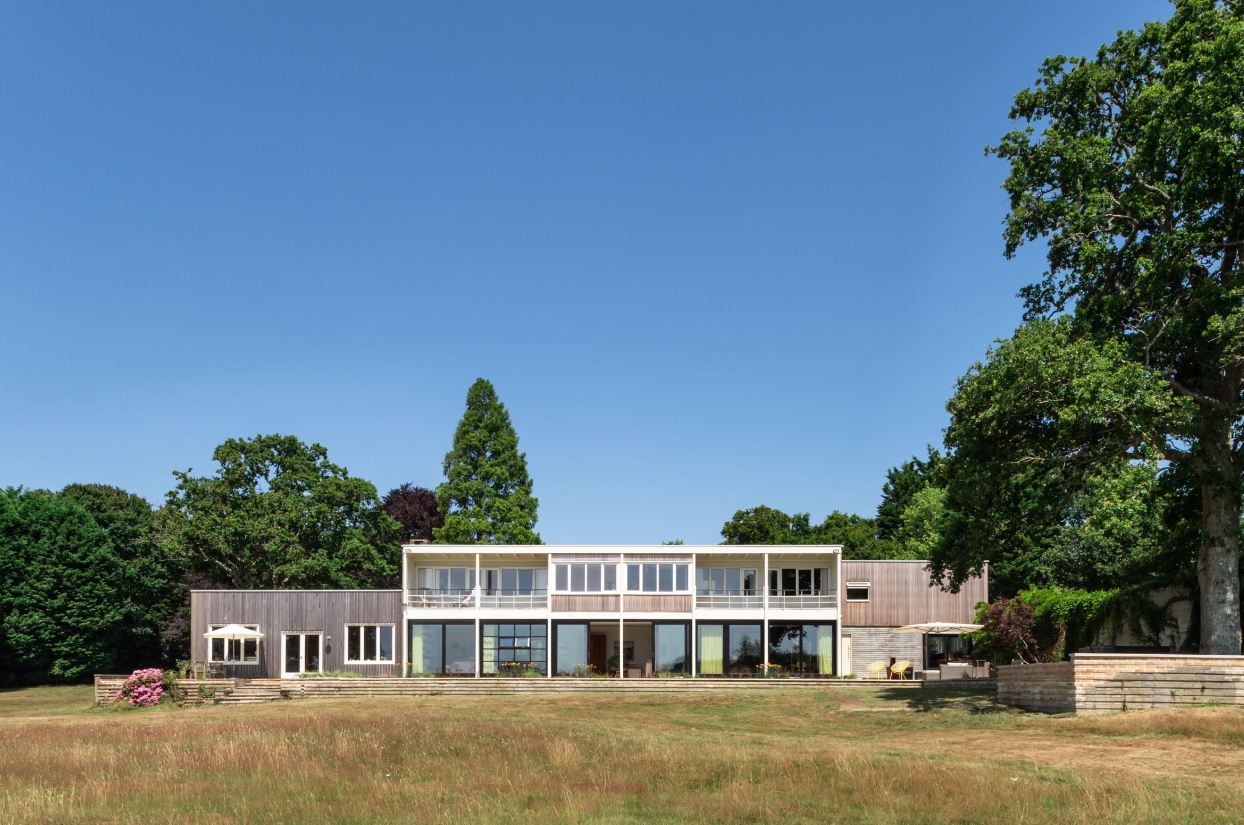 Flat-roofed timber clad house surrounded by trees