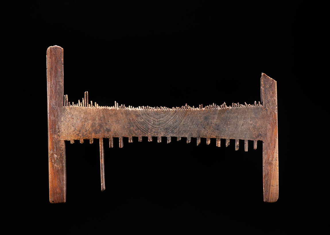 A nit comb which is has lost most of the teeth. The remnants of the teeth show how one side would have been fine-toothed, and the other side had wider spread teeth.