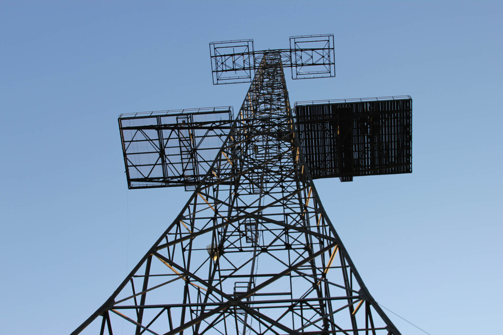 The metal structure of the Chain Home Tower rising into the blue sky
