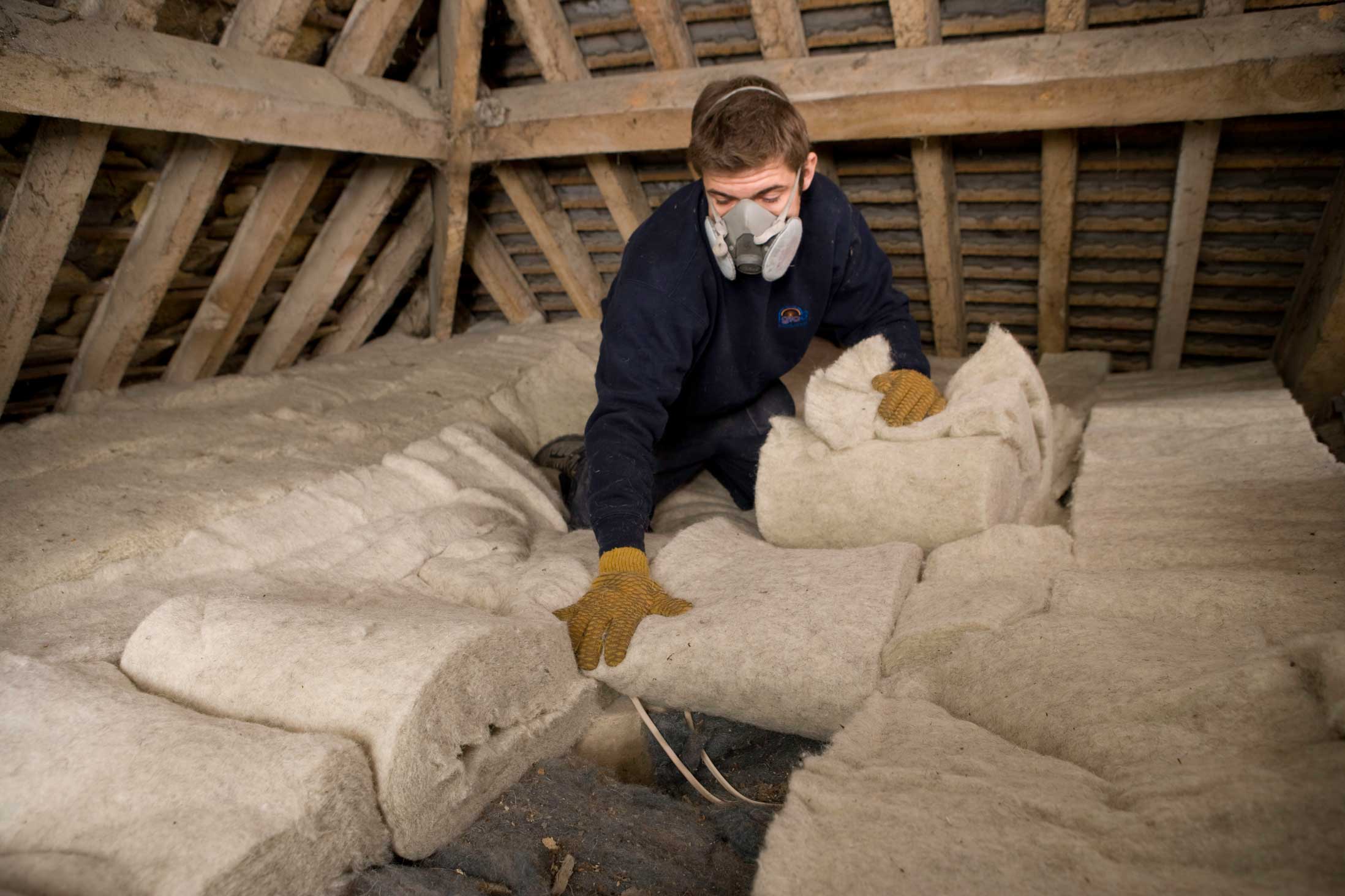 Man laying insulation in loft.