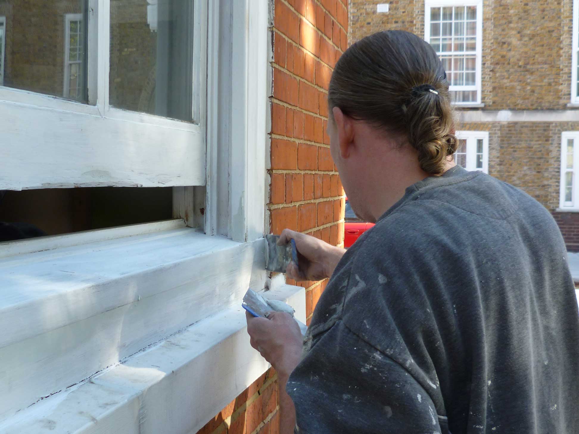 A man painting window sill.