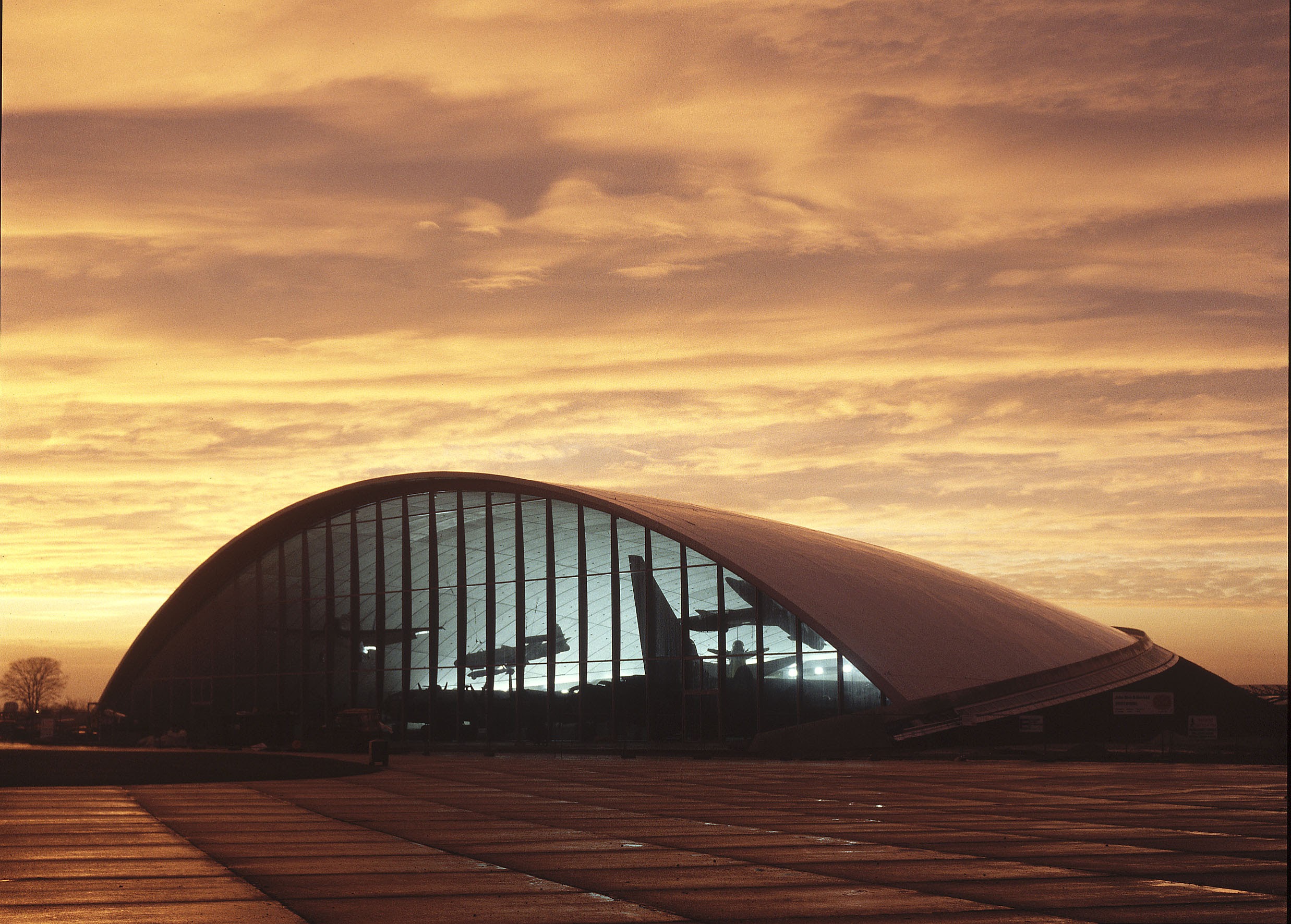 View of hangar at sunset with silhouettes of aircraft inside the building