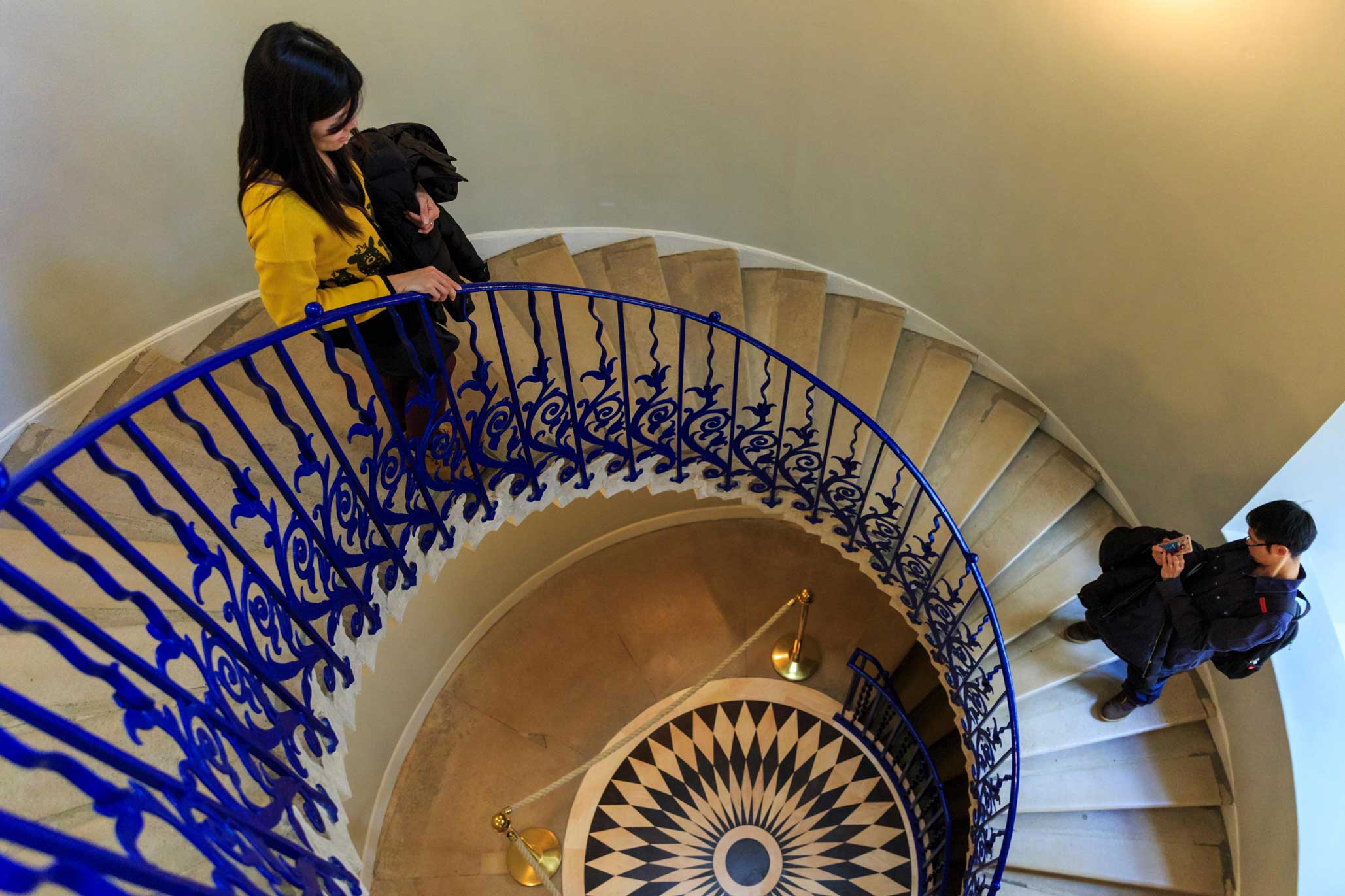 Two people standing on a metal spiral staircase.
