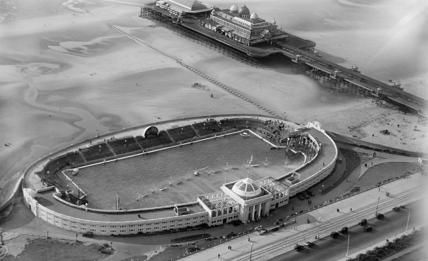 Aerial view of an open-air swimming pool set within an oval building