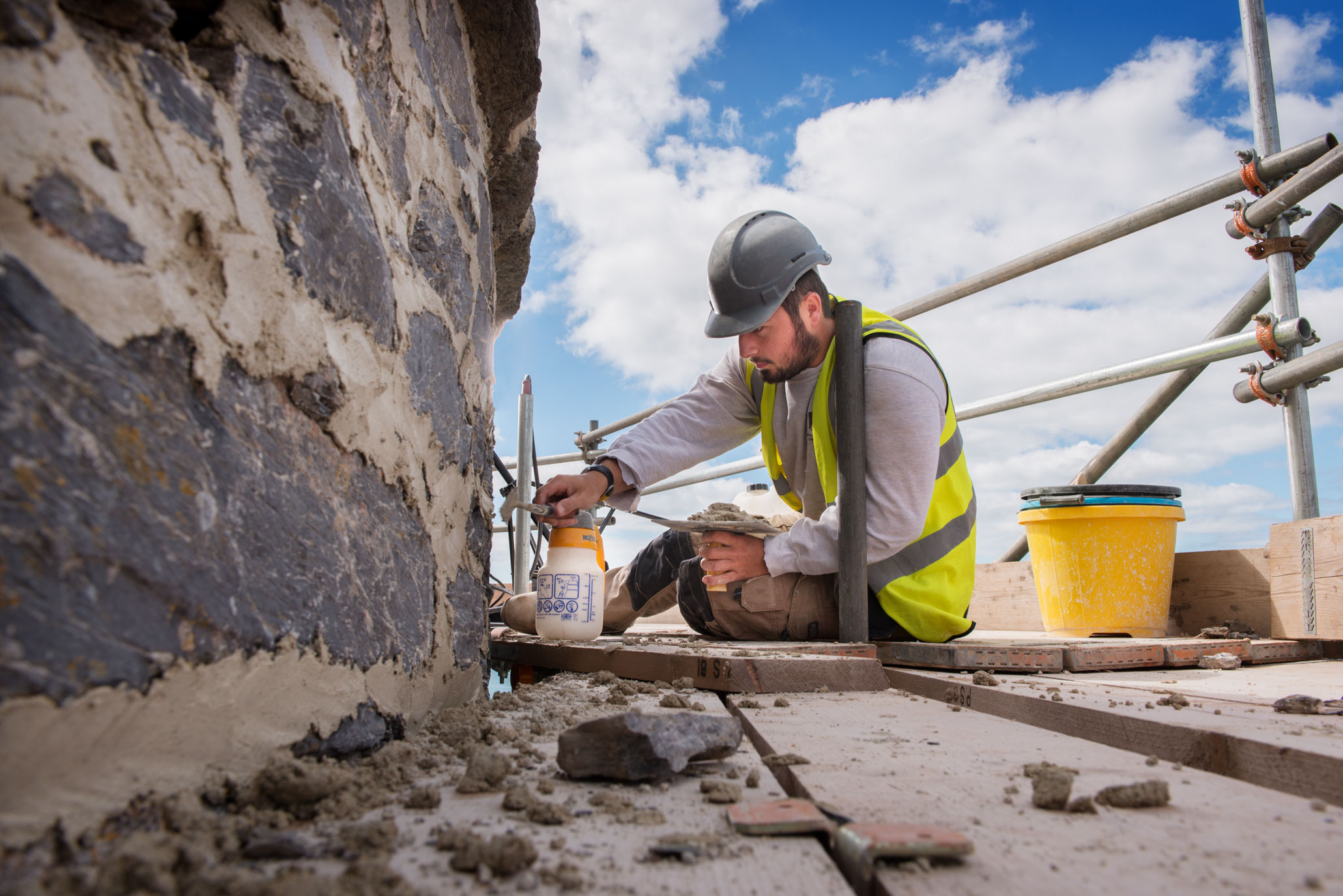 A man on scaffolding repointing a historic structure