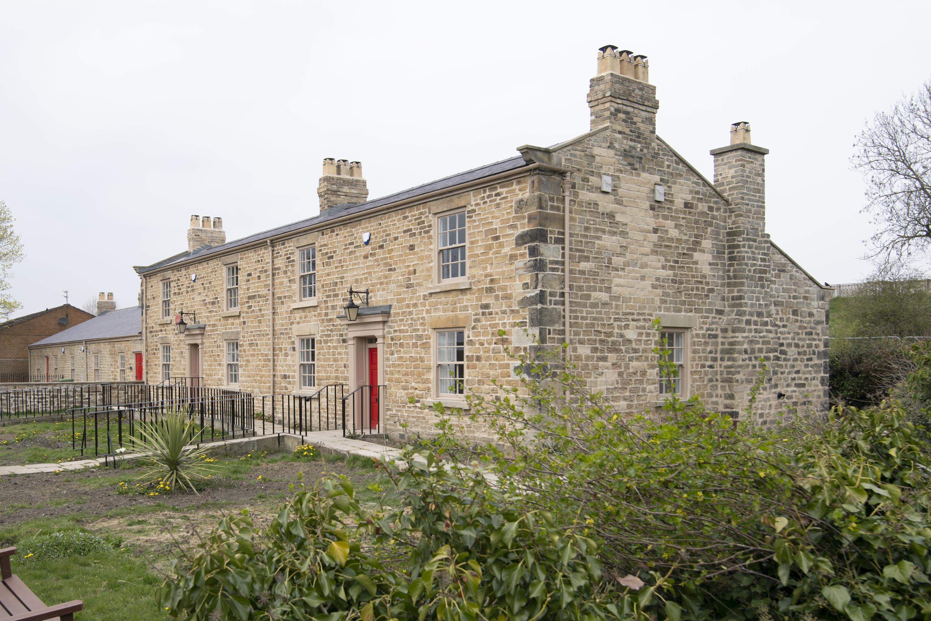 19th-century semi-detached stone cottage with ivy hedge and threadbare lawn in the foreground.