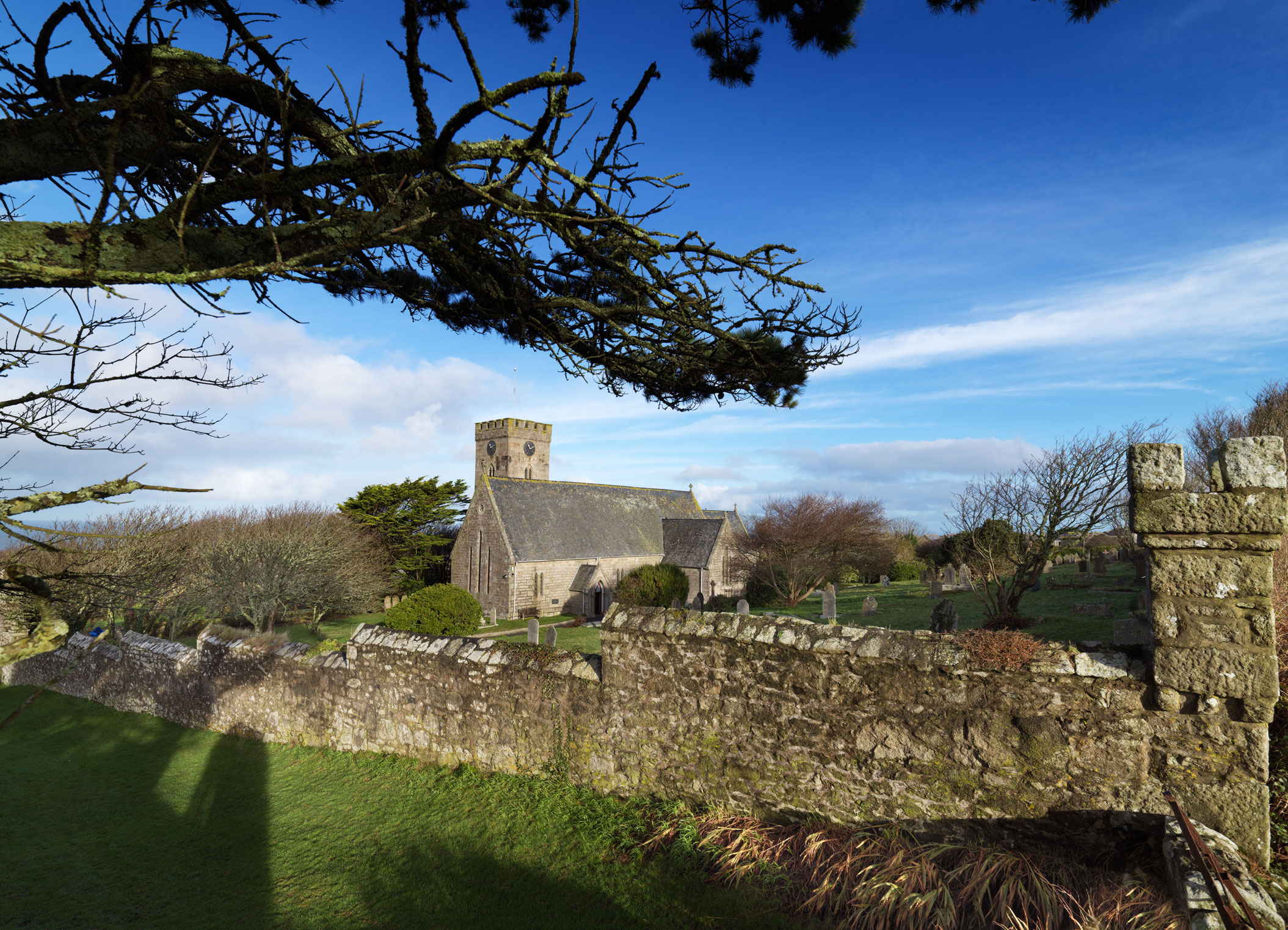 A stone-built church with a boundary wall in the foreground.