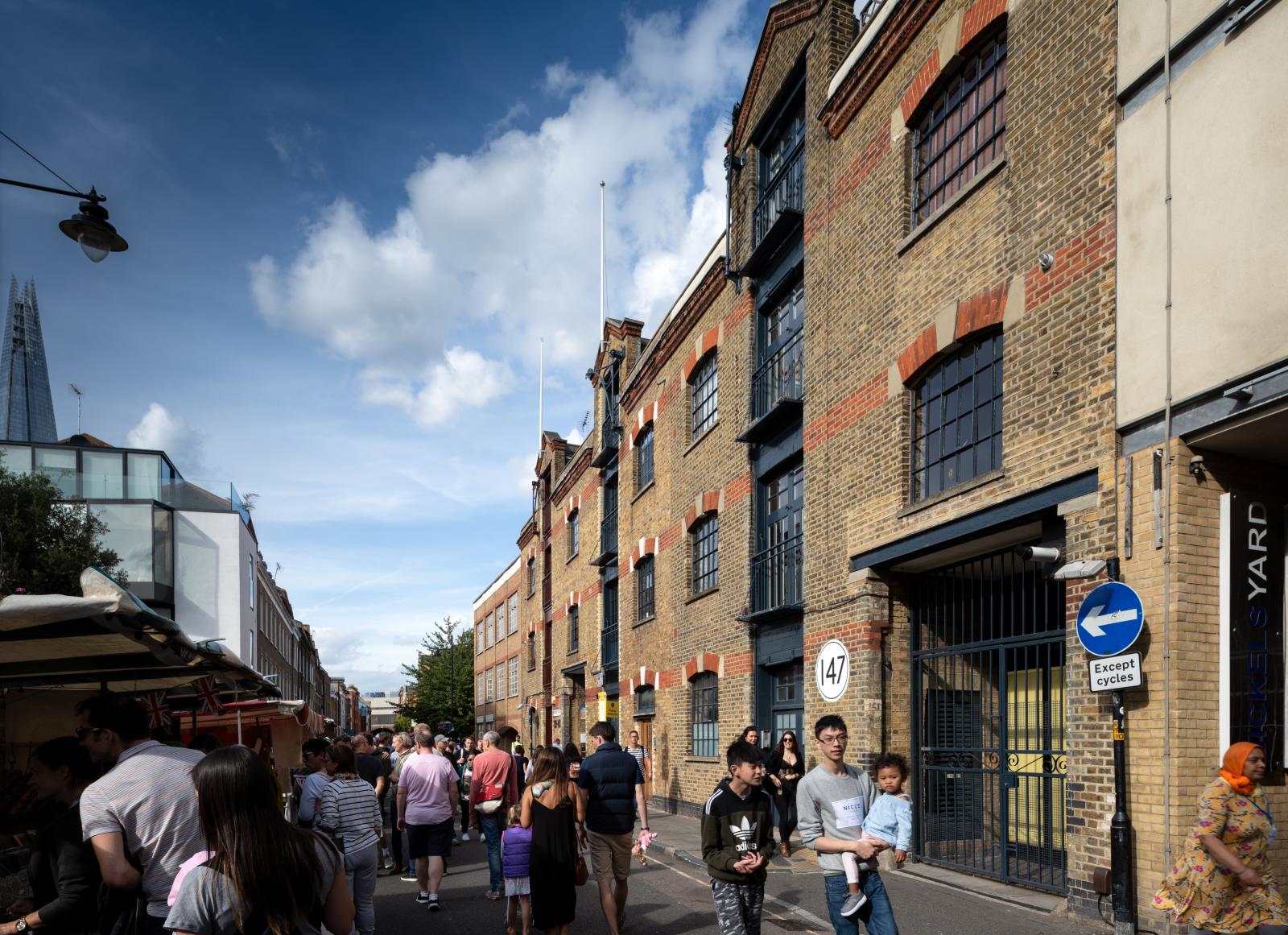 A photo of Bermondsey Street Festival, showing people in the street next to historic warehouse buildings.