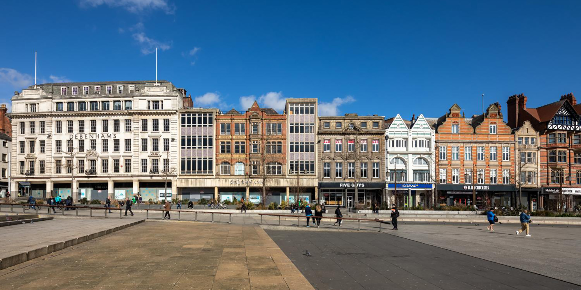 A series of historic shop fronts in a pedestrianised area of a city.
