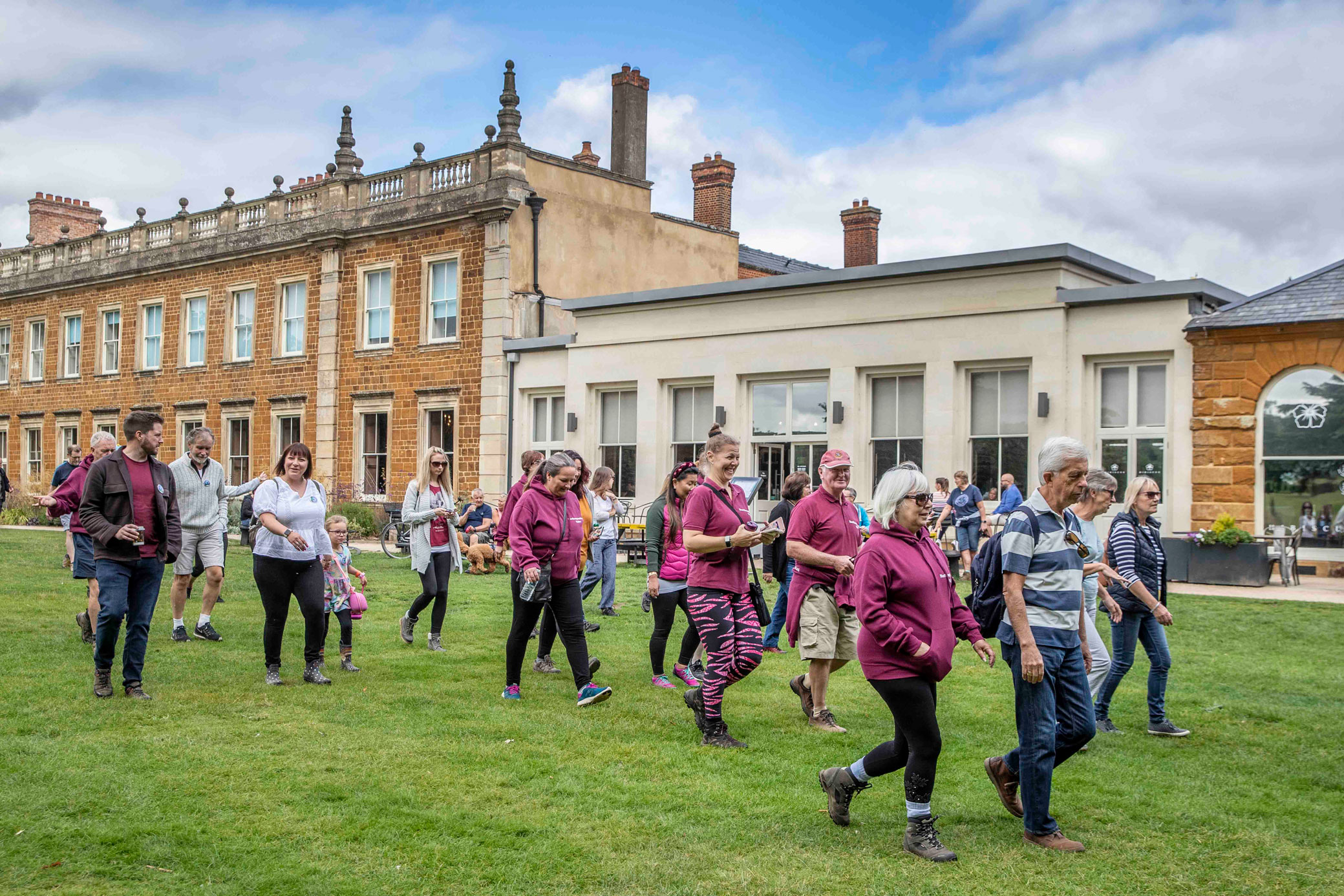 A group of people walking in the grounds of a country house.