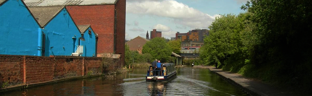 View along a canal in Birmingham, with canal boat and industrial buildings.