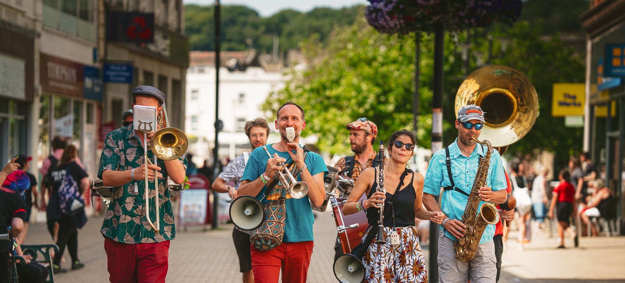 A troup of musicians walk along Weston-super-Mare high street paying wind instruments 