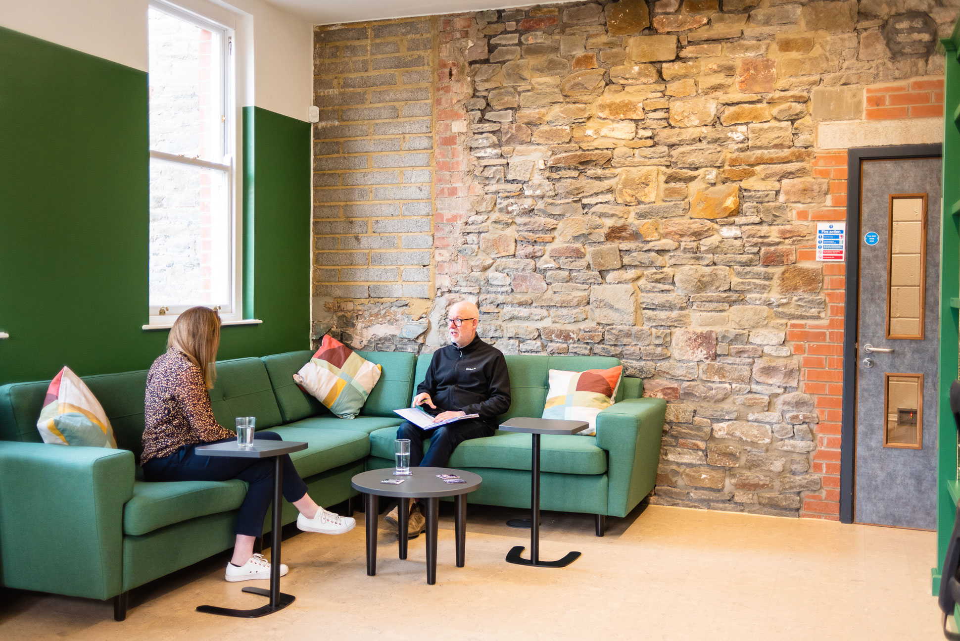 Two people are seated on a sofa having a business meeting.