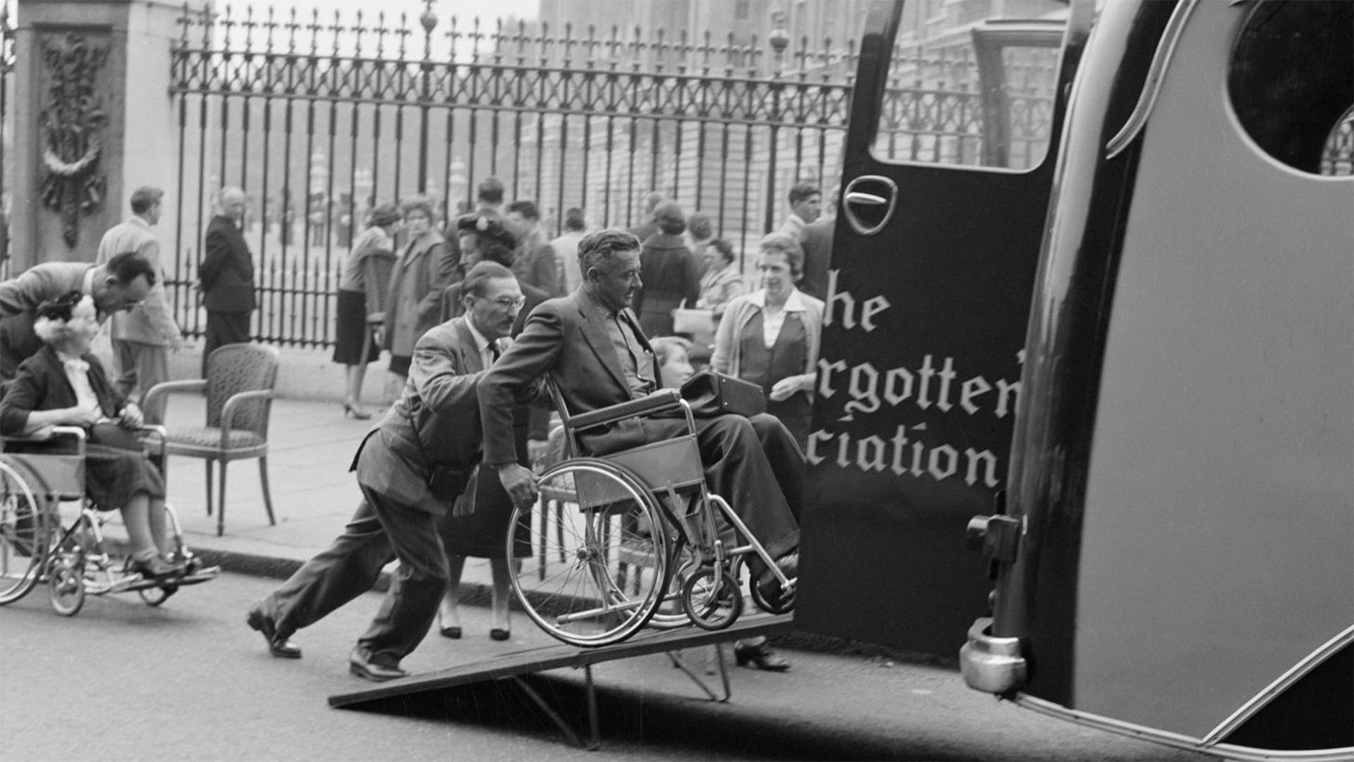 Man in a wheelchair being pushed up a ramp into the back of a van