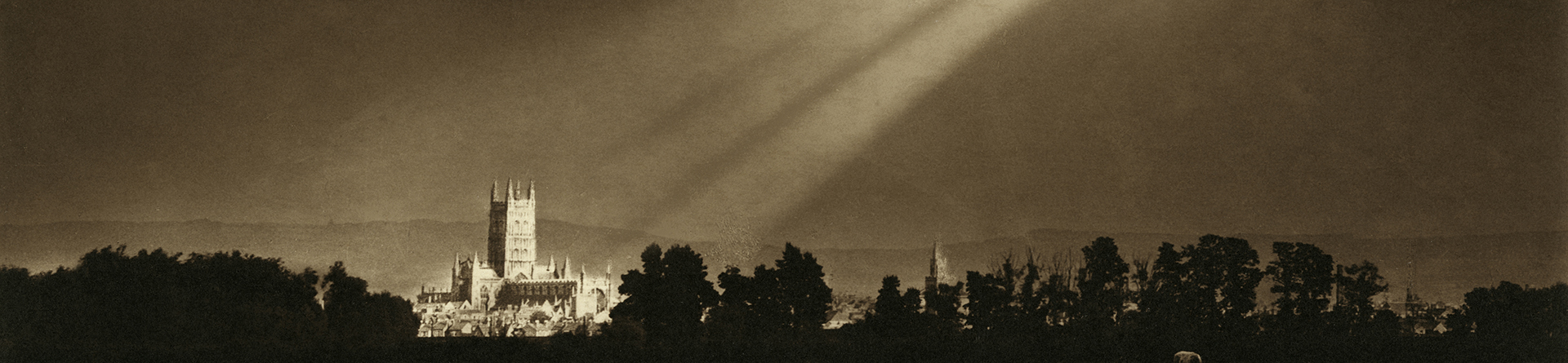 Archive photo of sunlight breaking through clouds and lighting Gloucester cathedral.