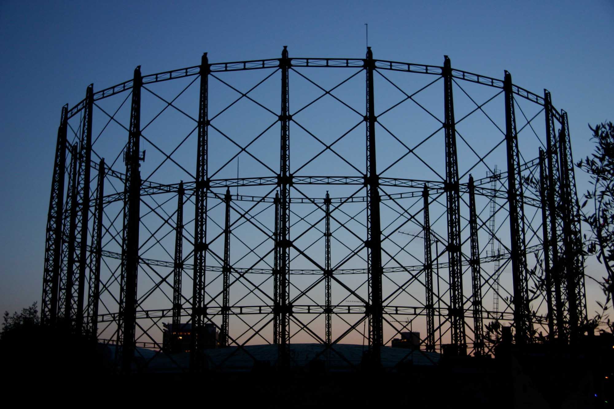 Gasholder at the Oval, London, in black silhouette against the sky at dusk.