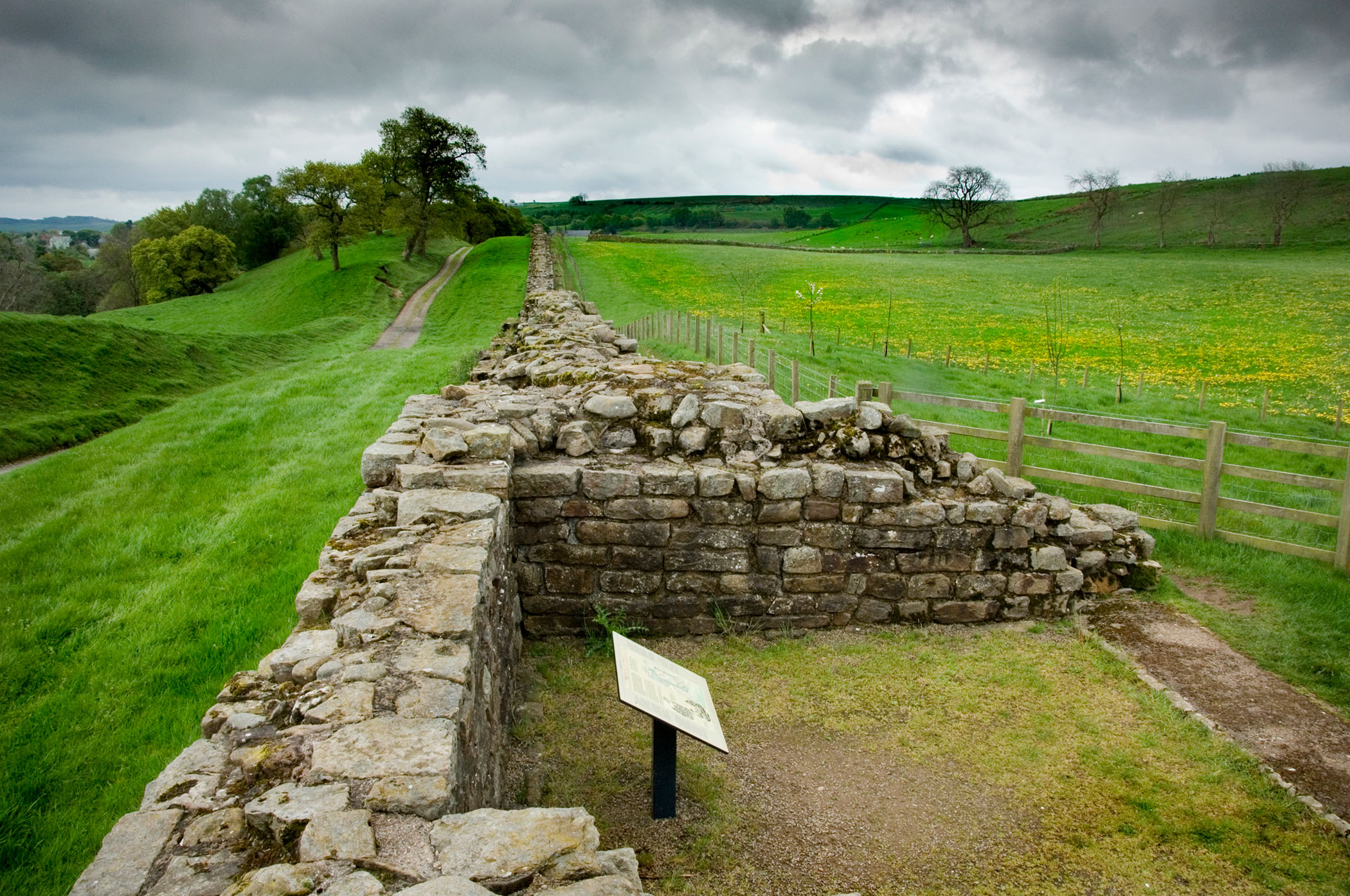 A photograph of Hadrian's Wall stretching off into the distance beneath dark clouds