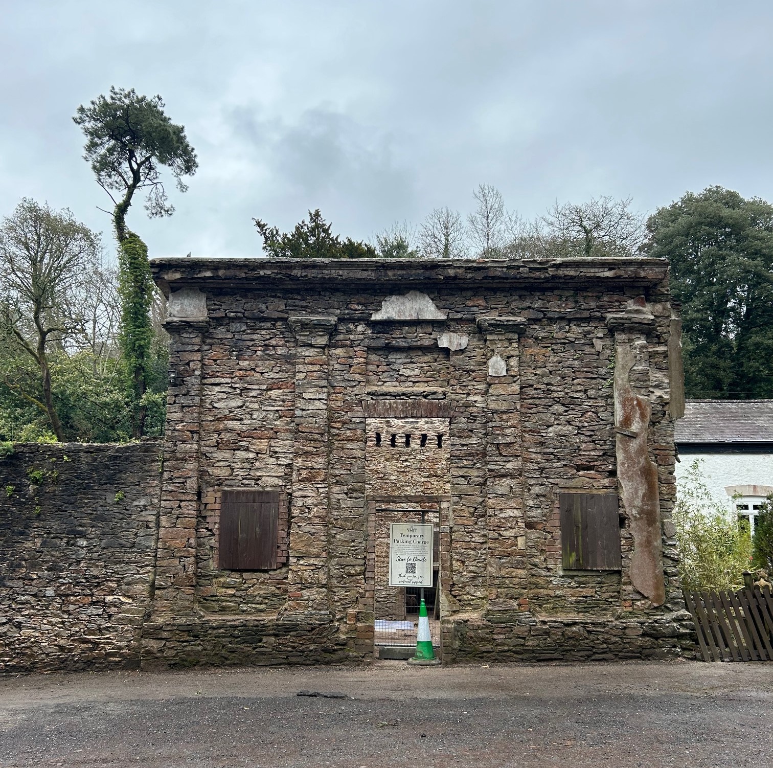 A photograph of the front of a newly repaired two-storey stone-built classical agricultural building.