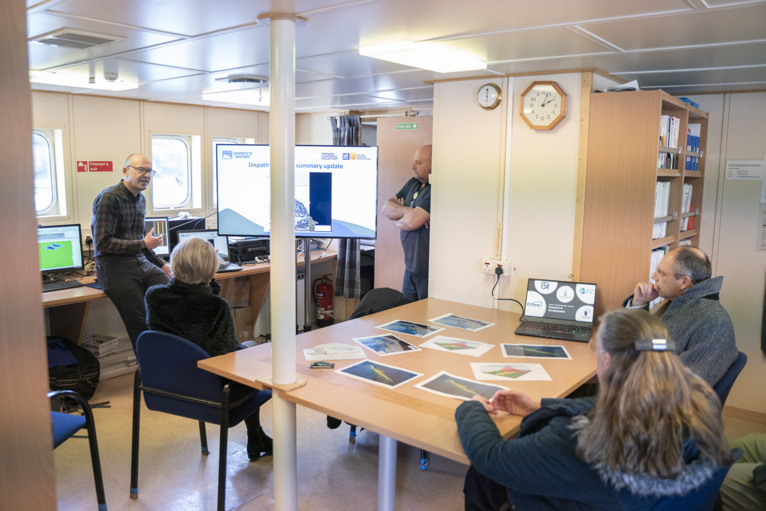 People sitting around a table listening to a presentation.