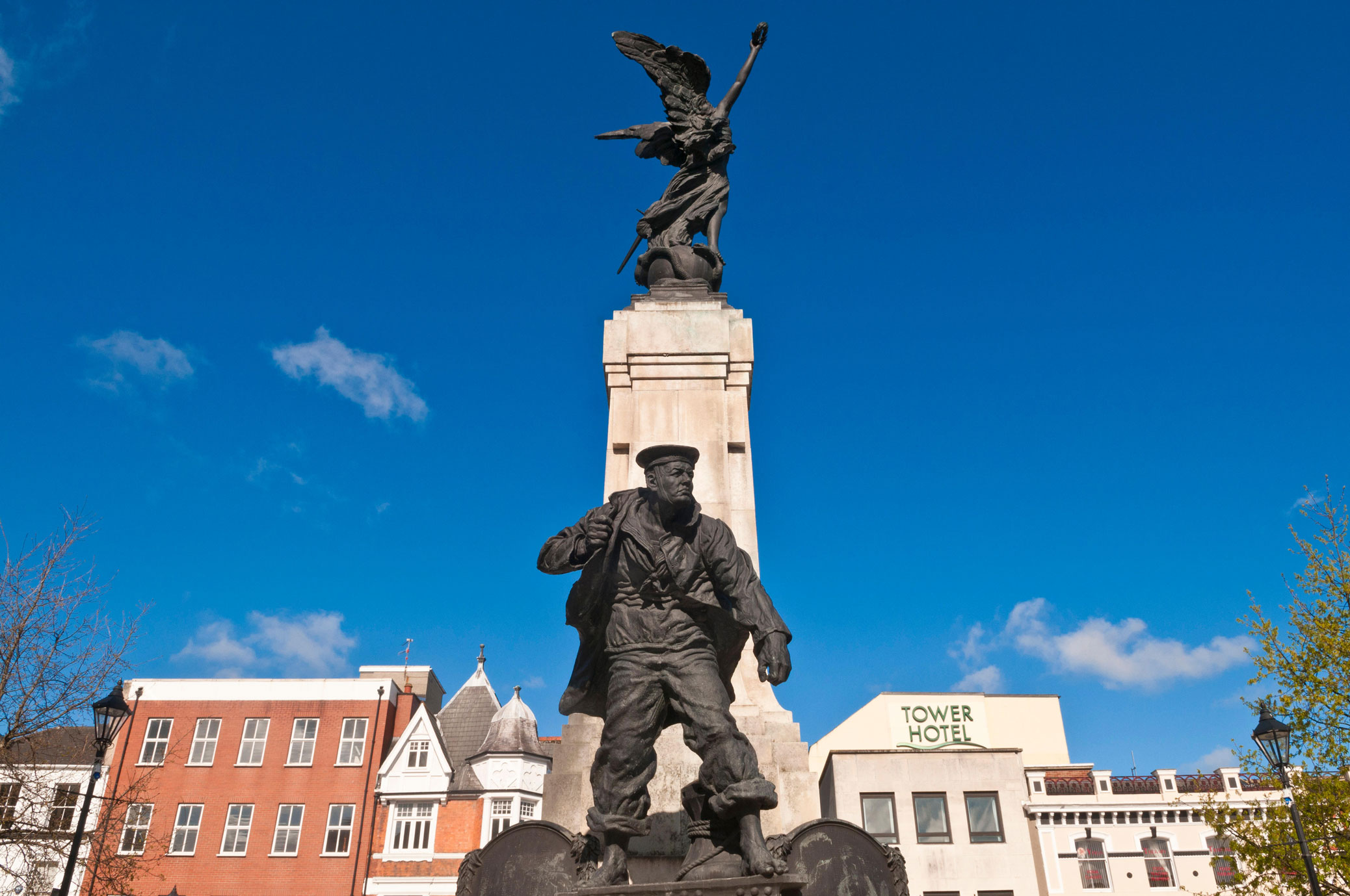 A war memorial with a winged victory atop a pillar, at the base is a group of statues representing different branches of the British armed services, in this image a sailor is prominent.