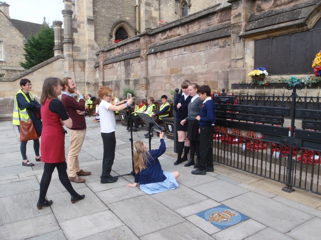 Schoolchildren and teachers filming outside a church.