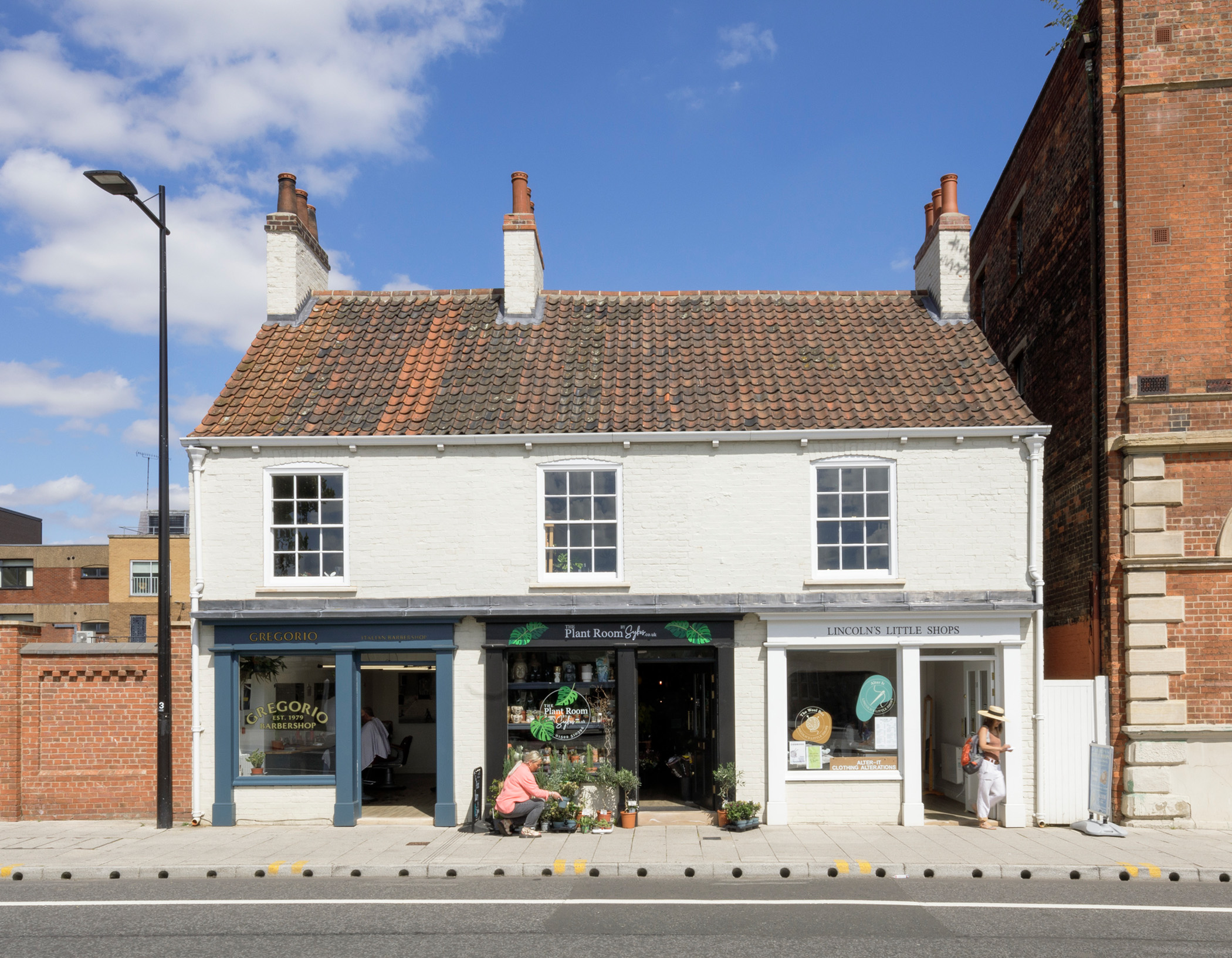 General view of a 2-storey building housing a row of 3 shops following renovation work