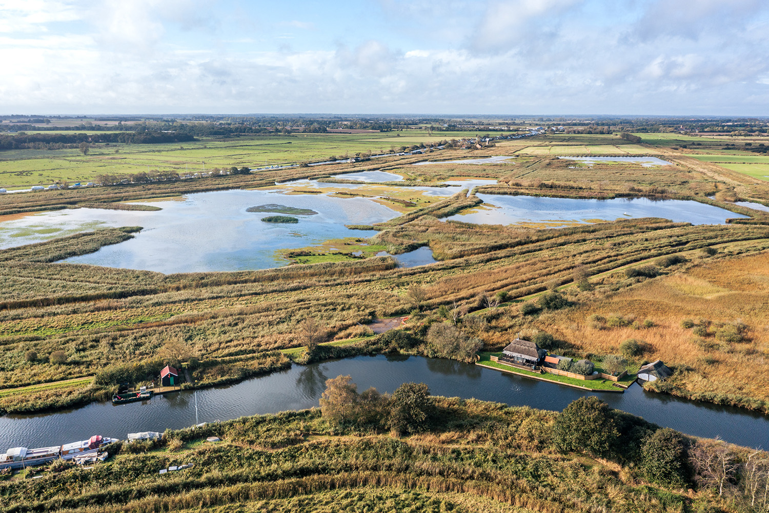 Aerial view with a waterway in the foreground and ponds in the background.