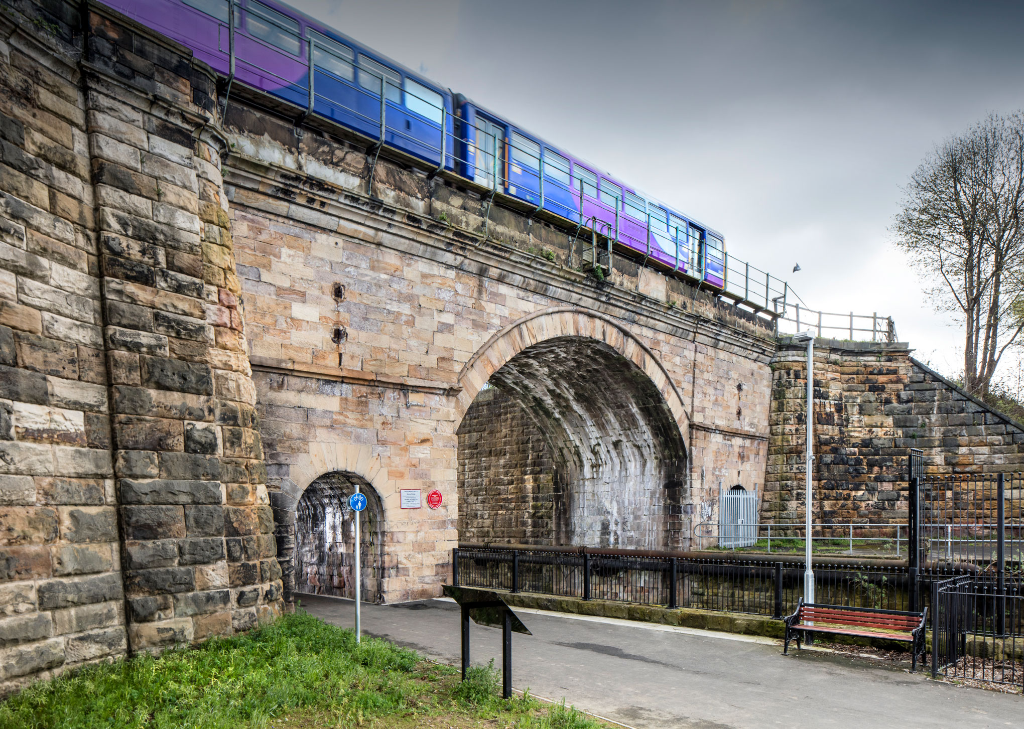 Photograph of a stone ashlar bridge with  train passing over it.