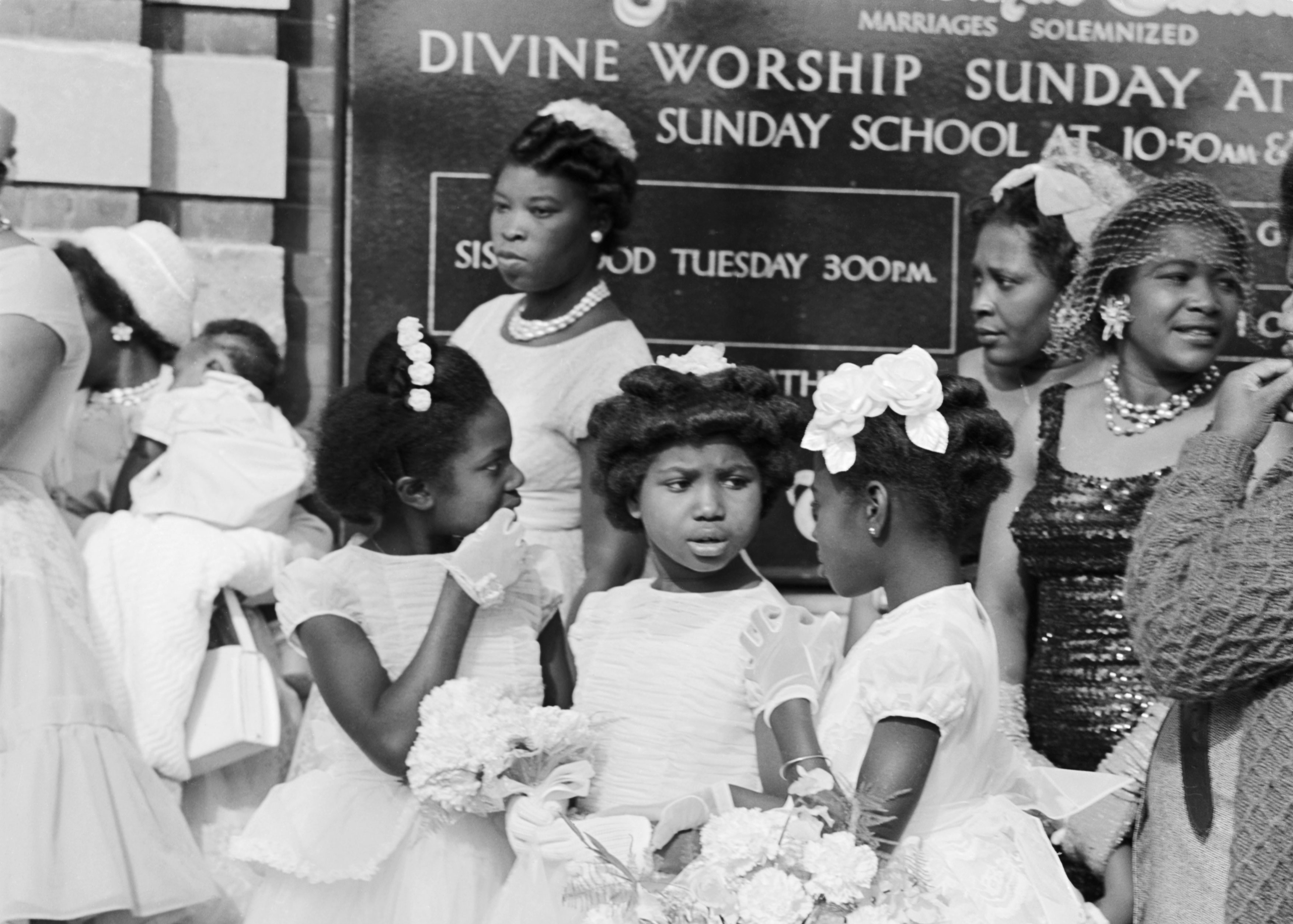 Three young black girls chatting outside a Methodist chapel, possibly Aylesbury, 1950-59