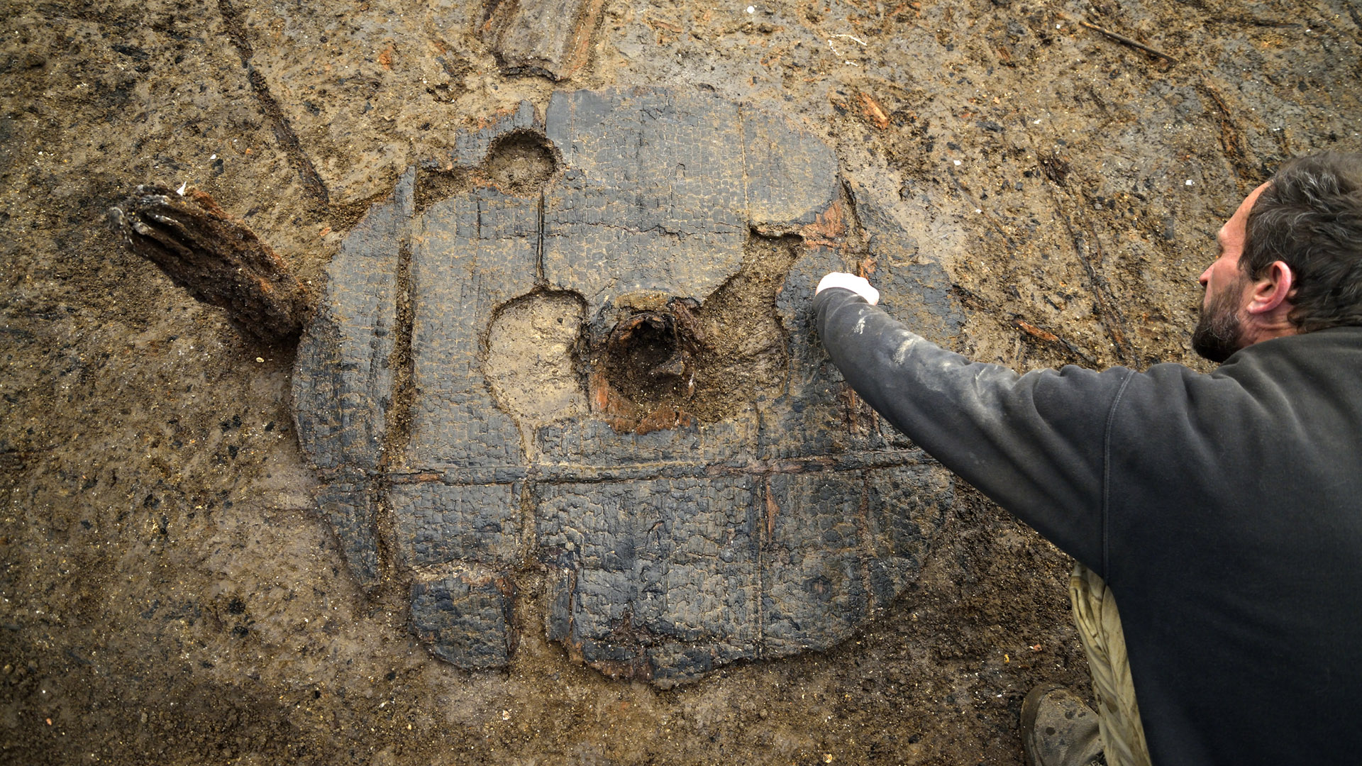 Man cleaning a bronze age wheel on site at Must Farm