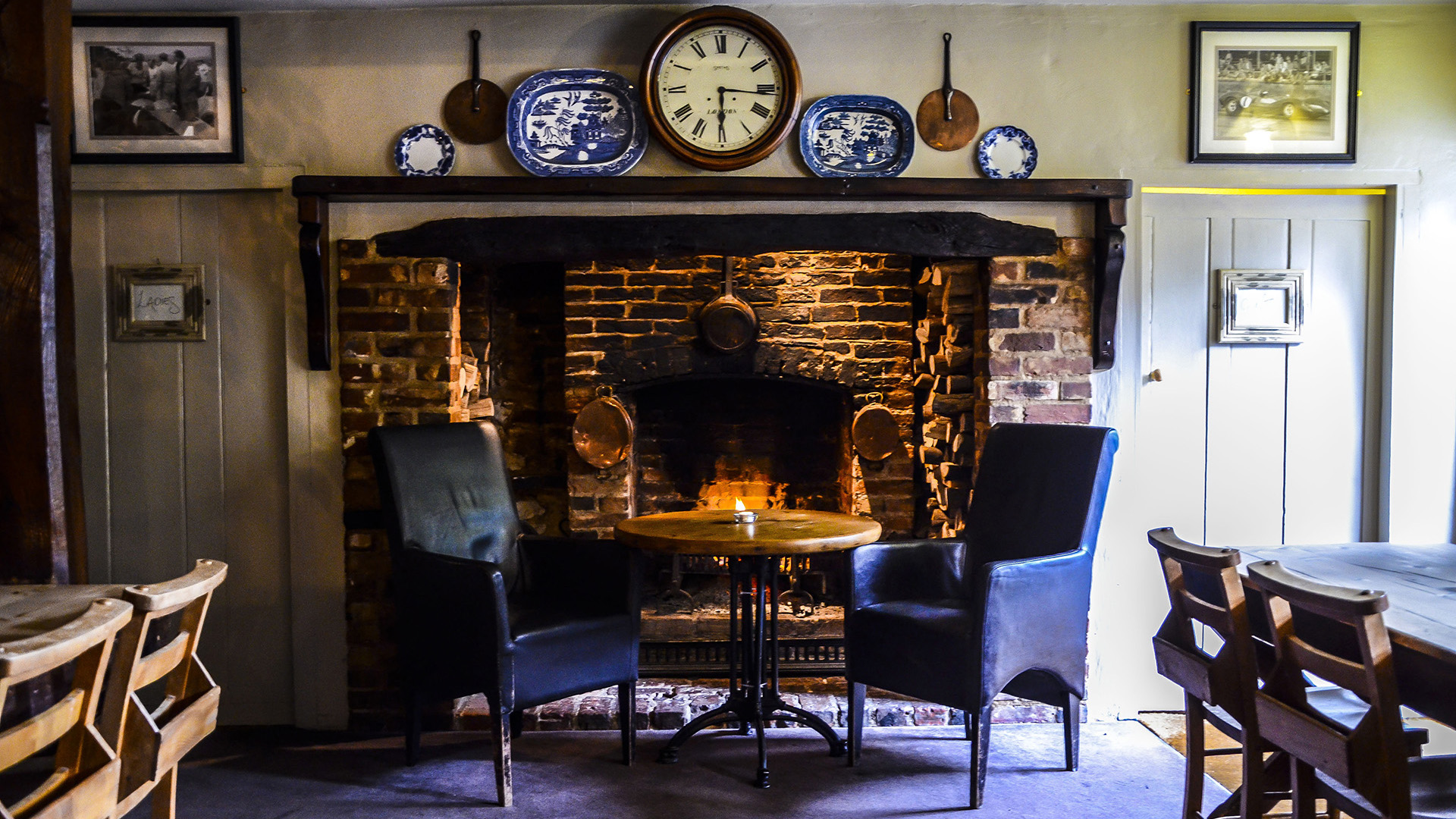 Armchairs in front of an open fire in the Hat Rack bar