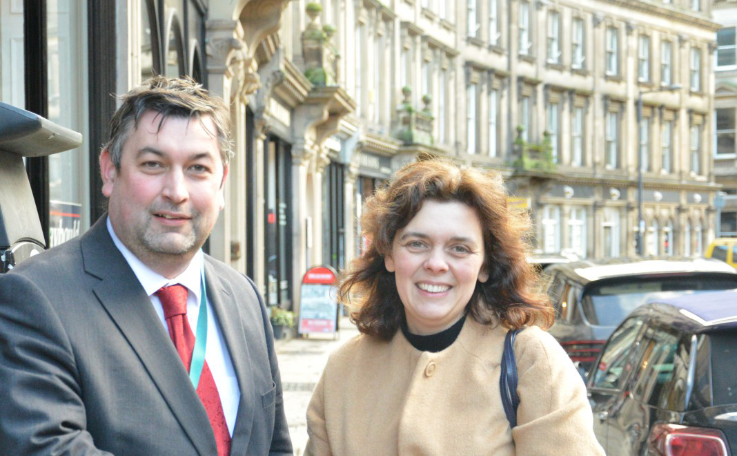 A man and woman stand on a pavement on the Strand in Derby shaking hands 