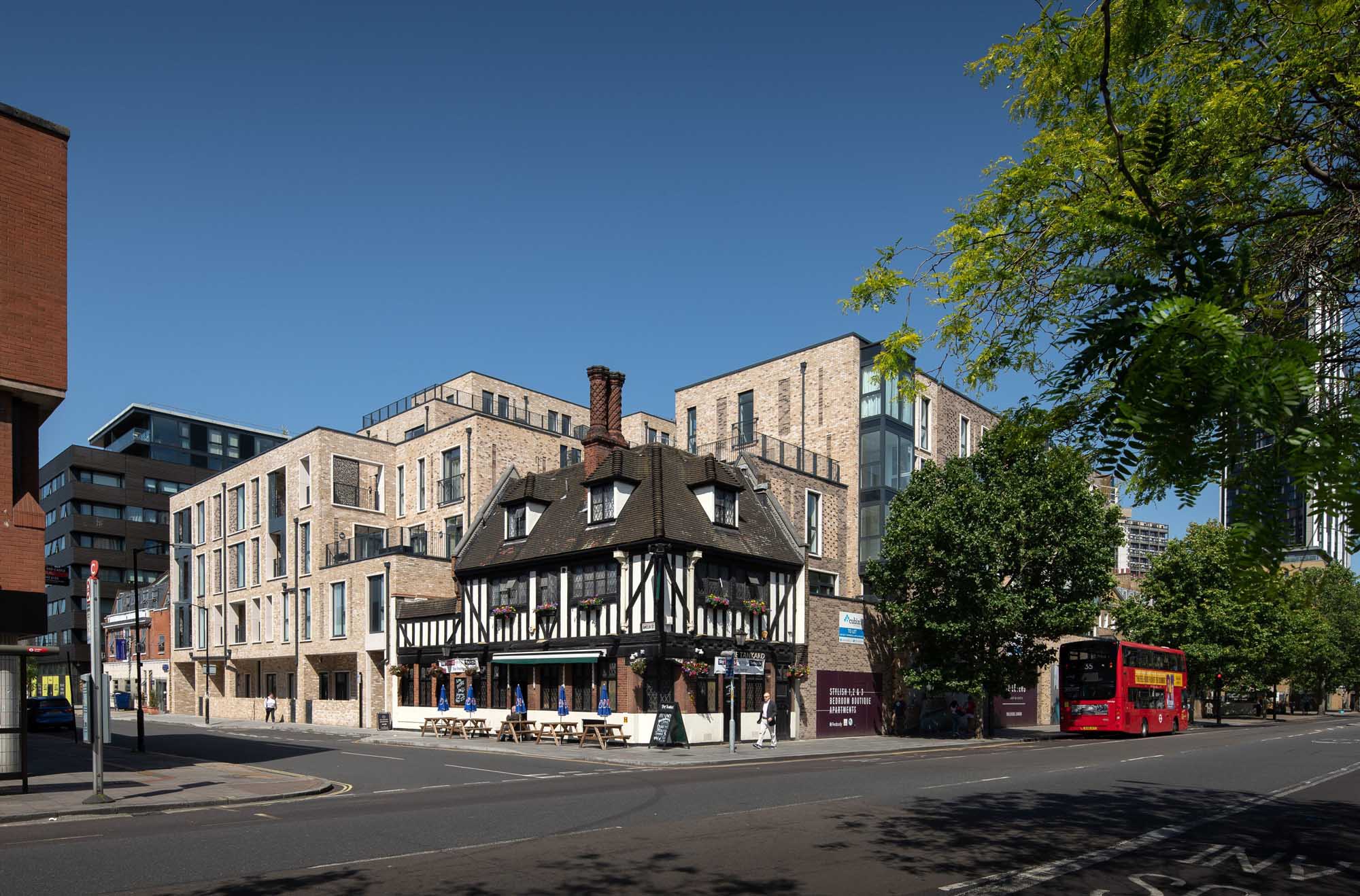 Black and white timber-framed building surrounded by modern housing blocks