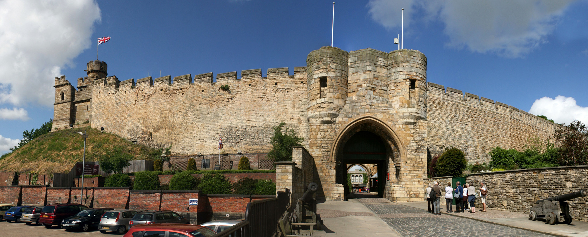 The walls of a large English castle beneath a blue sky with clouds