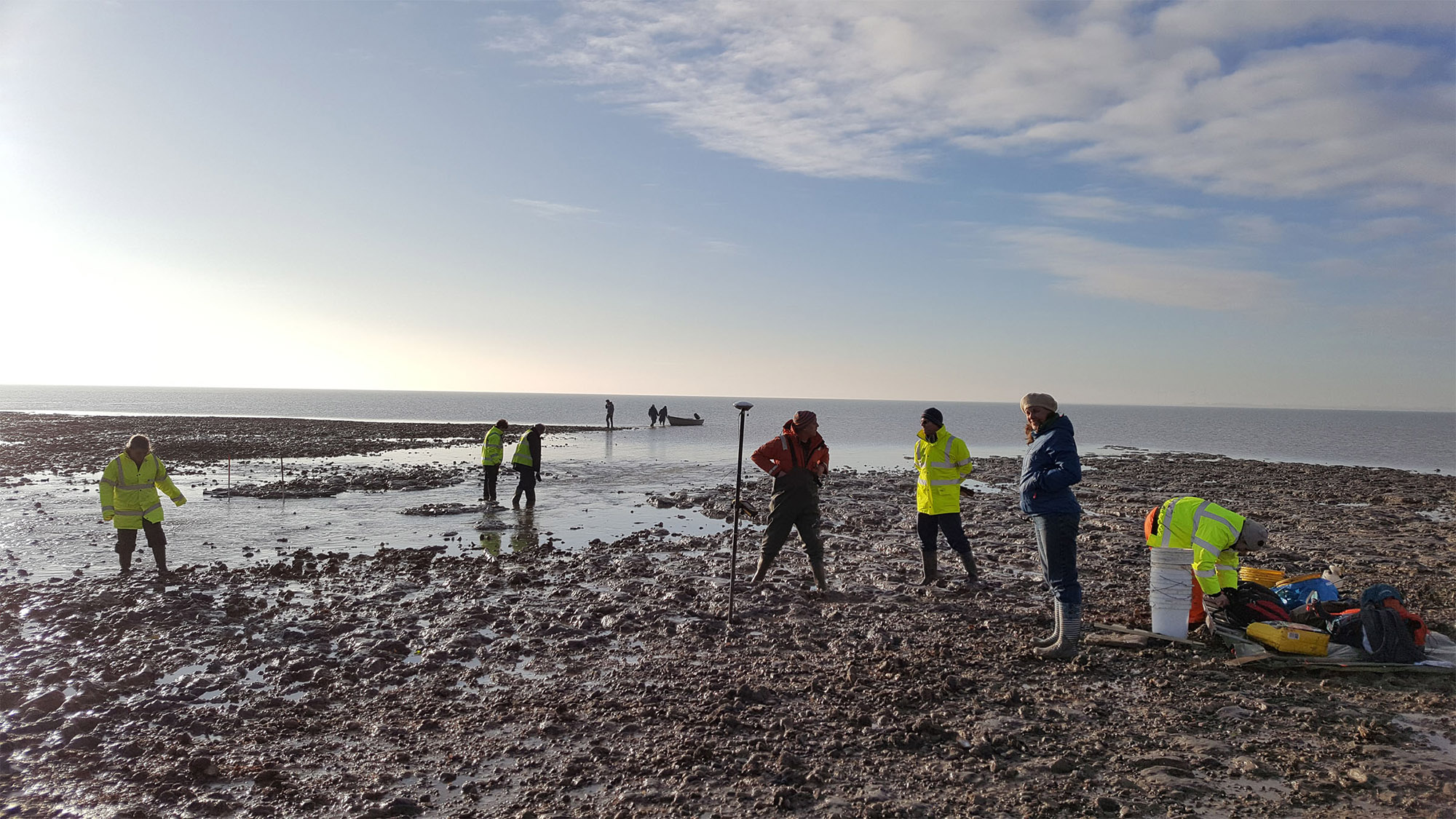 People in high-viz jackets carrying out a survey on a beach.