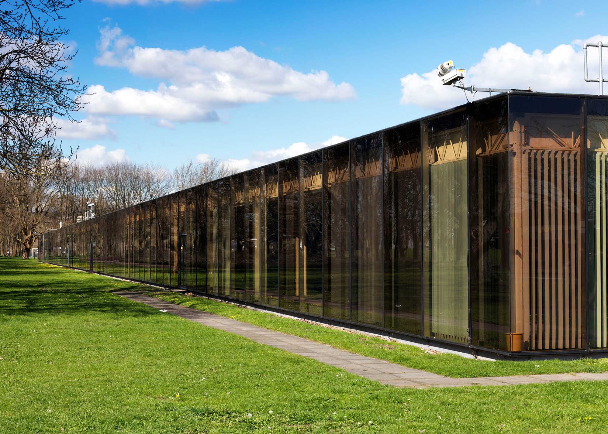 A glass one-storey office building surrounded by grass.
