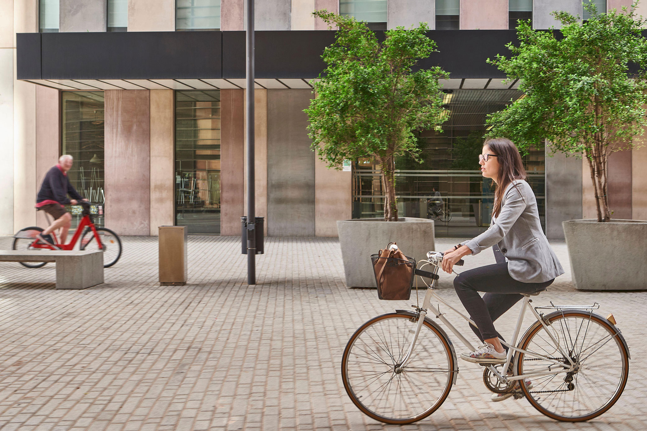 A woman on a bicycle is cycling through a town centre.