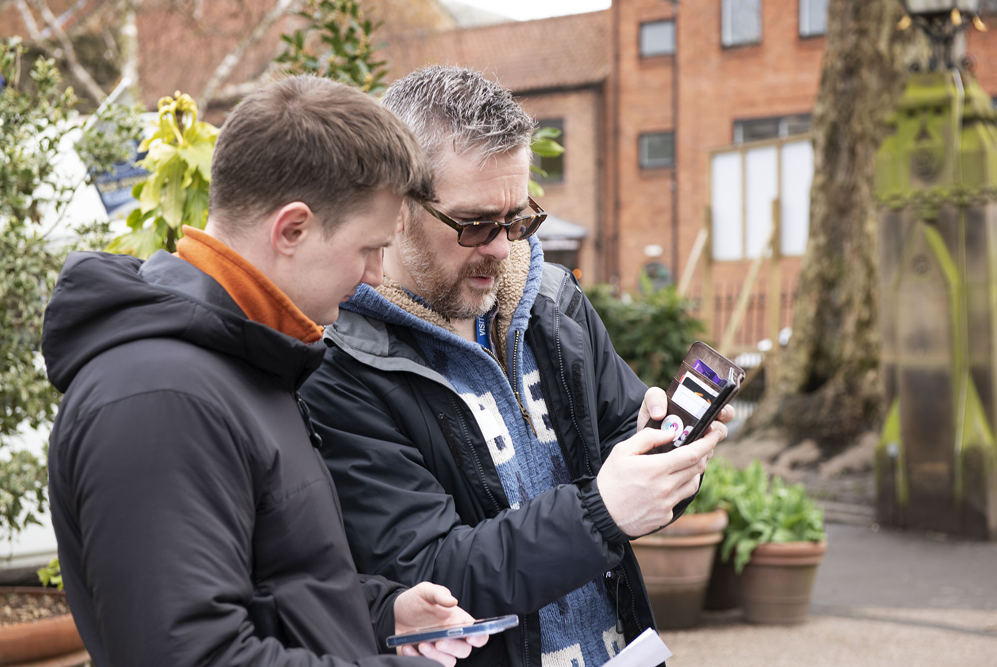 Two people on their mobile phones standing close together