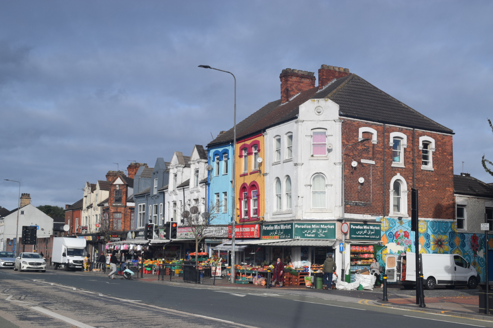 A terraced row of shops next two a road. 