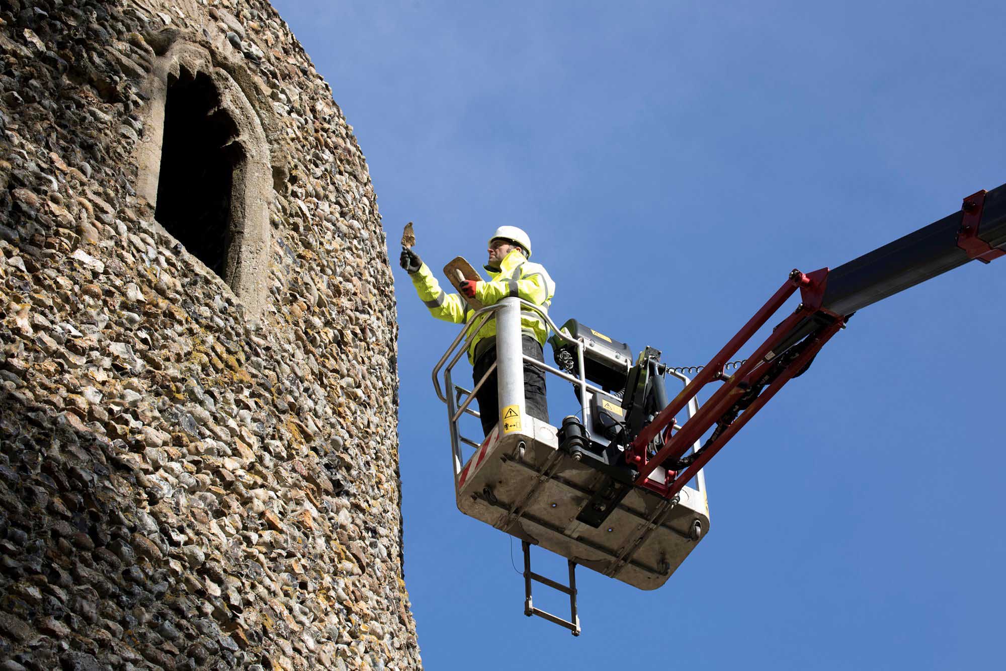 Man in cherry picker examining church tower